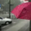 Person holding a pink umbrella in the rain