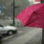 Person holding a pink umbrella in the rain