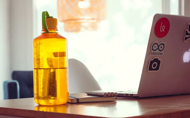 Orange water bottle next to a laptop